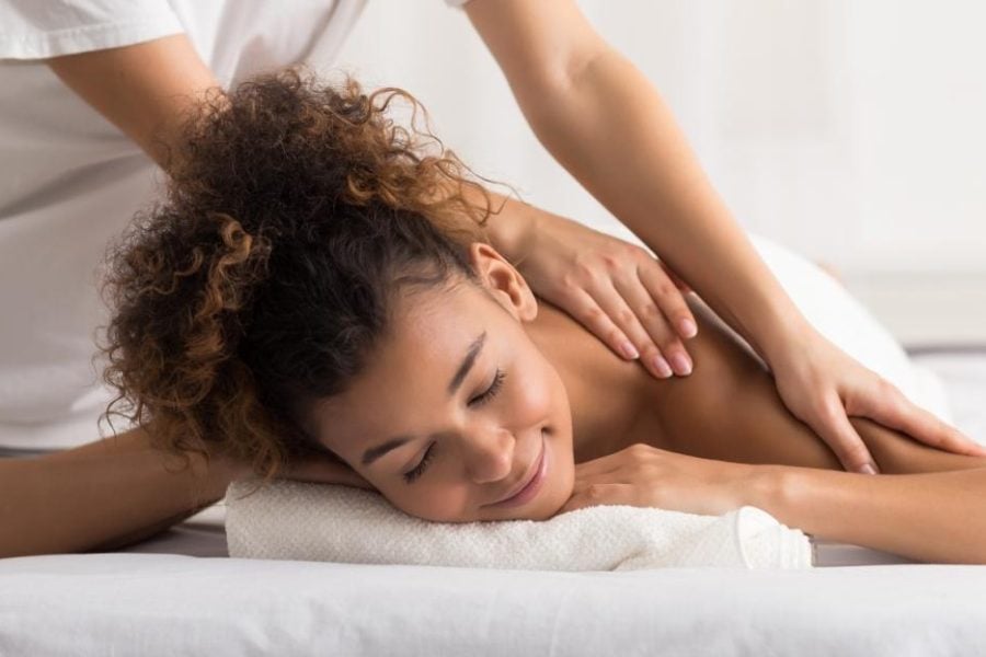 woman enjoying shoulder massage and relaxing in spa center